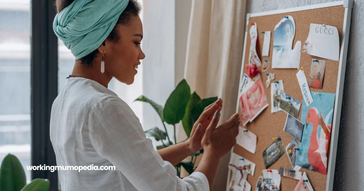 A woman wearing a teal headwrap and a white shirt is creating a vision board in a cozy, well-lit room. The corkboard is pinned with colorful pictures and inspirational words, symbolizing goals and aspirations. A plant and large windows in the background add a peaceful, motivating atmosphere.