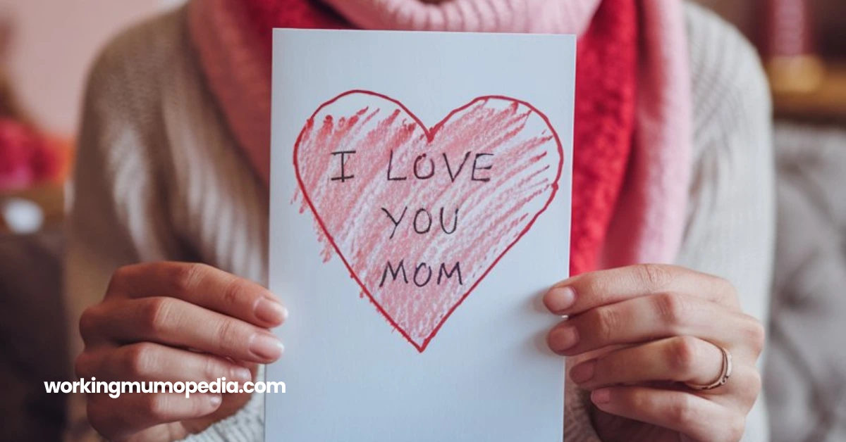 Close-up of a person holding a handmade Valentine's Day card with a heart and the message 'I Love You Mom' drawn in red crayon, representing love and appreciation for mothers.